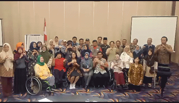 An animated GIF featuring a group of about 35 CIQAL workshop participants standing together as a group. They have varied disabilities, both visible and invisible. In unison, they are signing "FORKOMDESI, Sinduadi, tangguh," which translates to "Forkomdesi and Sinduadi village are disaster resilient."