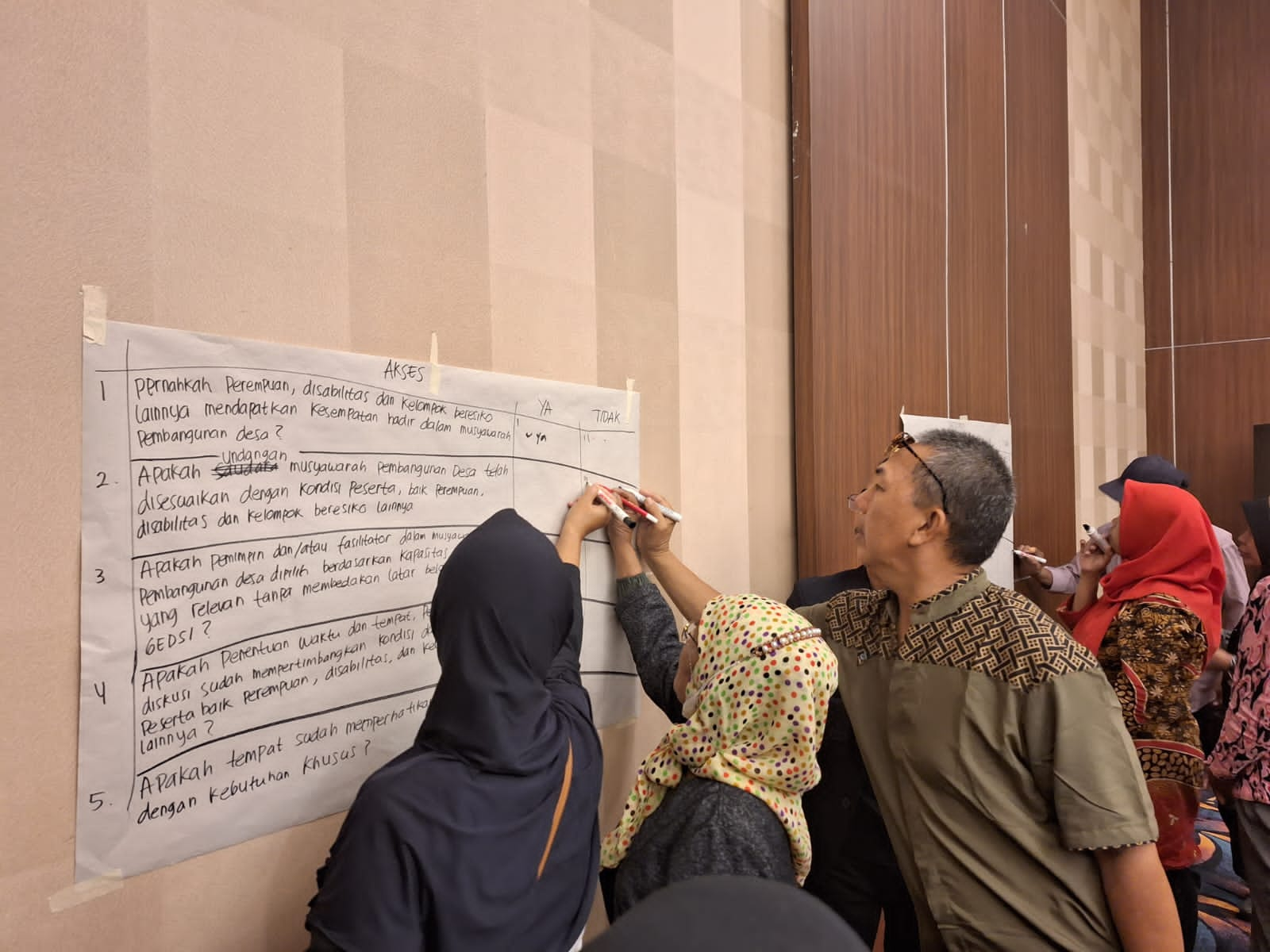 Workshop participants write together on a large piece of paper that is taped to the wall.