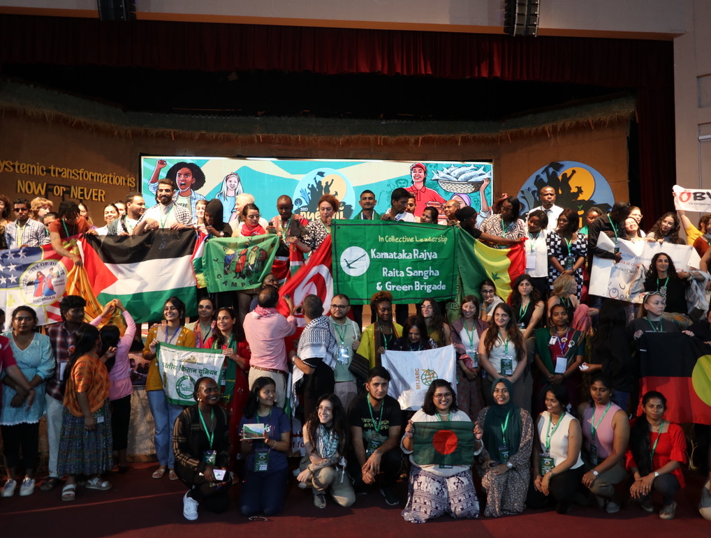 A photo of a diverse group of activists of varied races and gender presentations holding many colorful signs. Many are smiling.